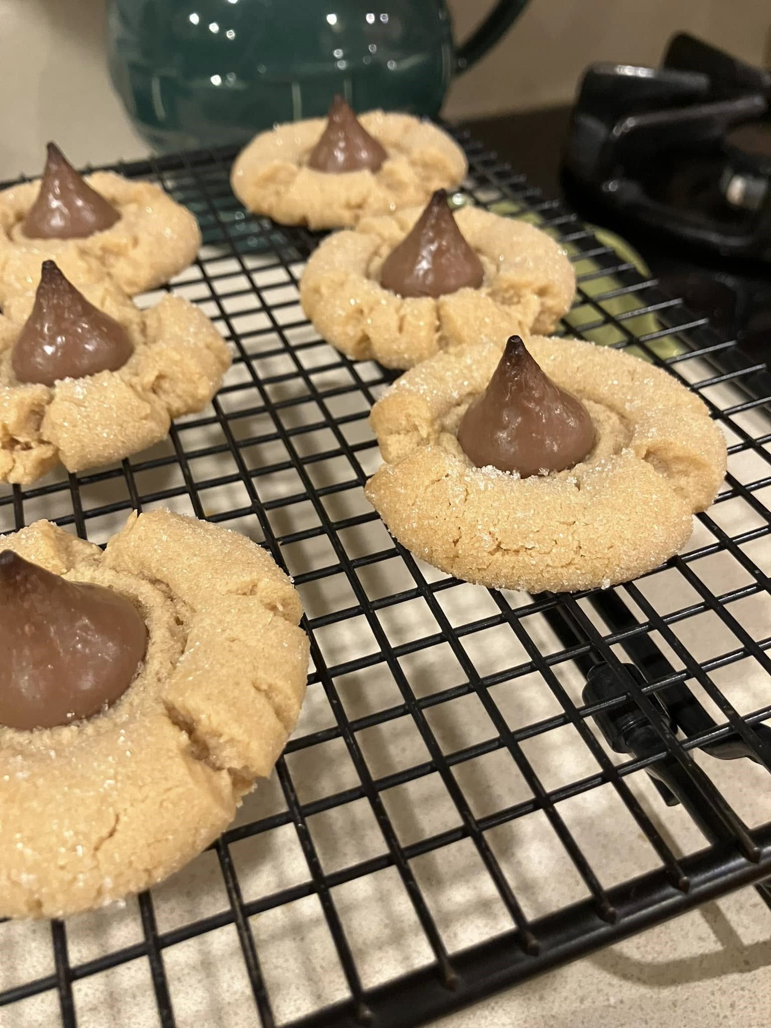peanut butter blossom cookies cooling on a black wire rack with Hershey’s Kisses in the center