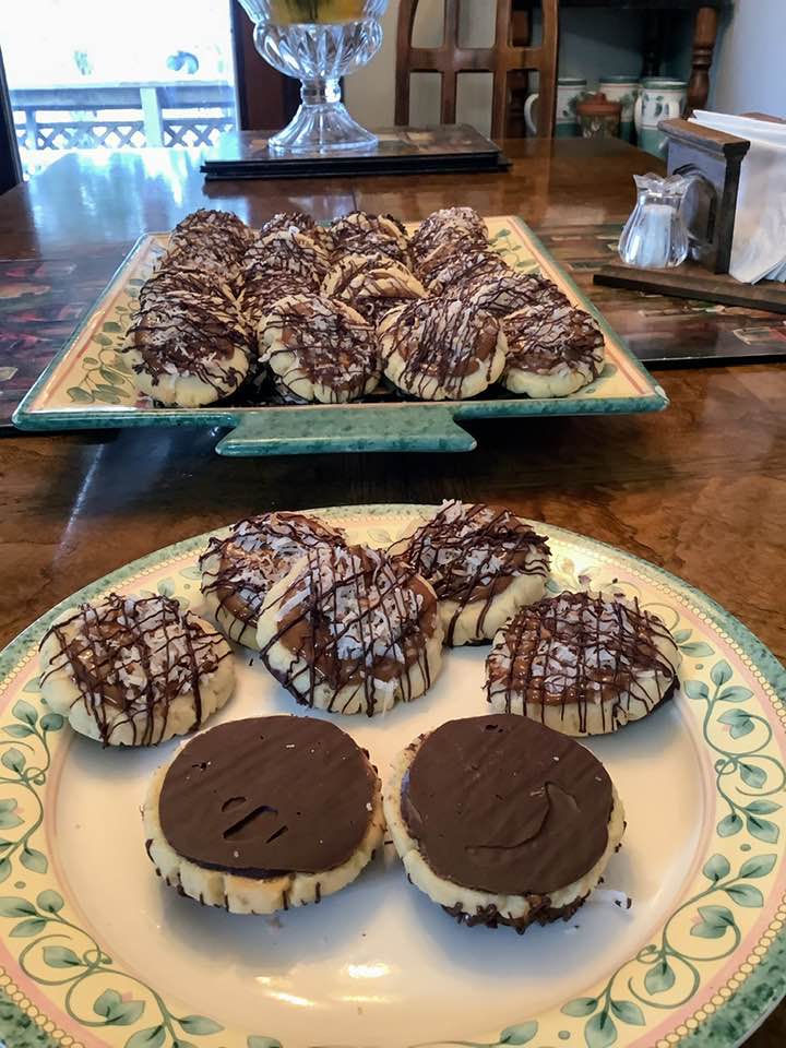 A close-up view of the finished Samoa cookies, some flipped over to reveal the smooth chocolate-coated bottom layer.