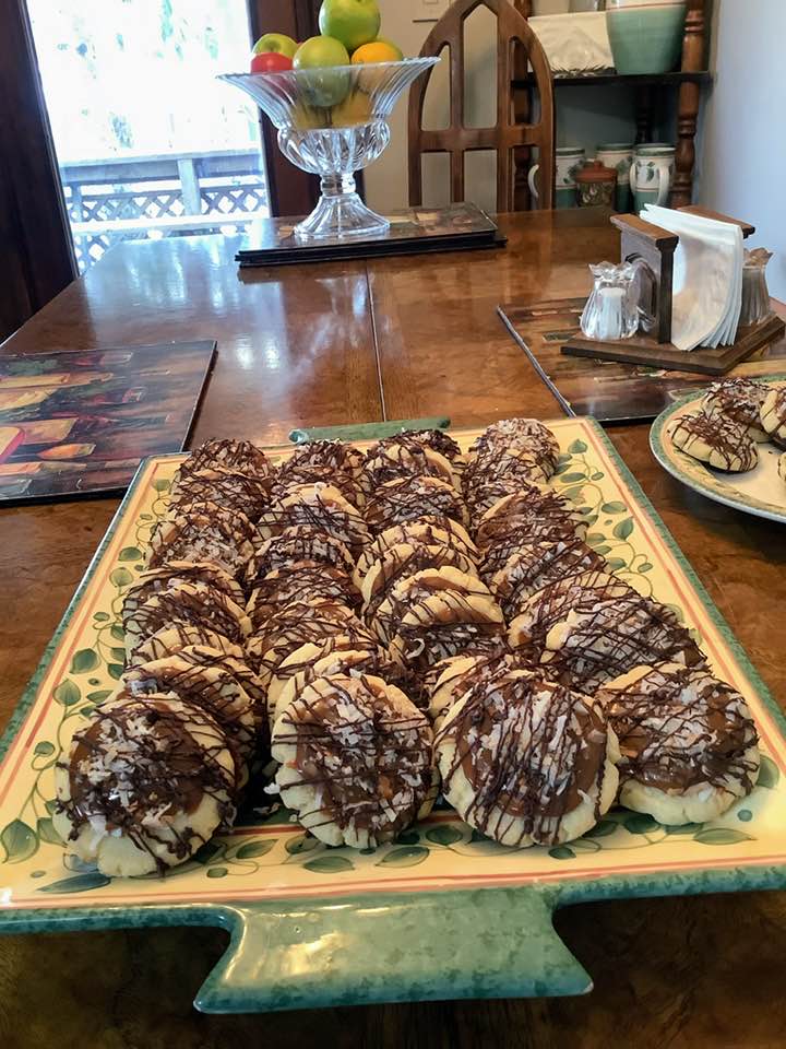 A large platter filled with dozens of homemade Samoa sugar cookies, showcasing the golden toasted coconut topping and zig-zag chocolate drizzle