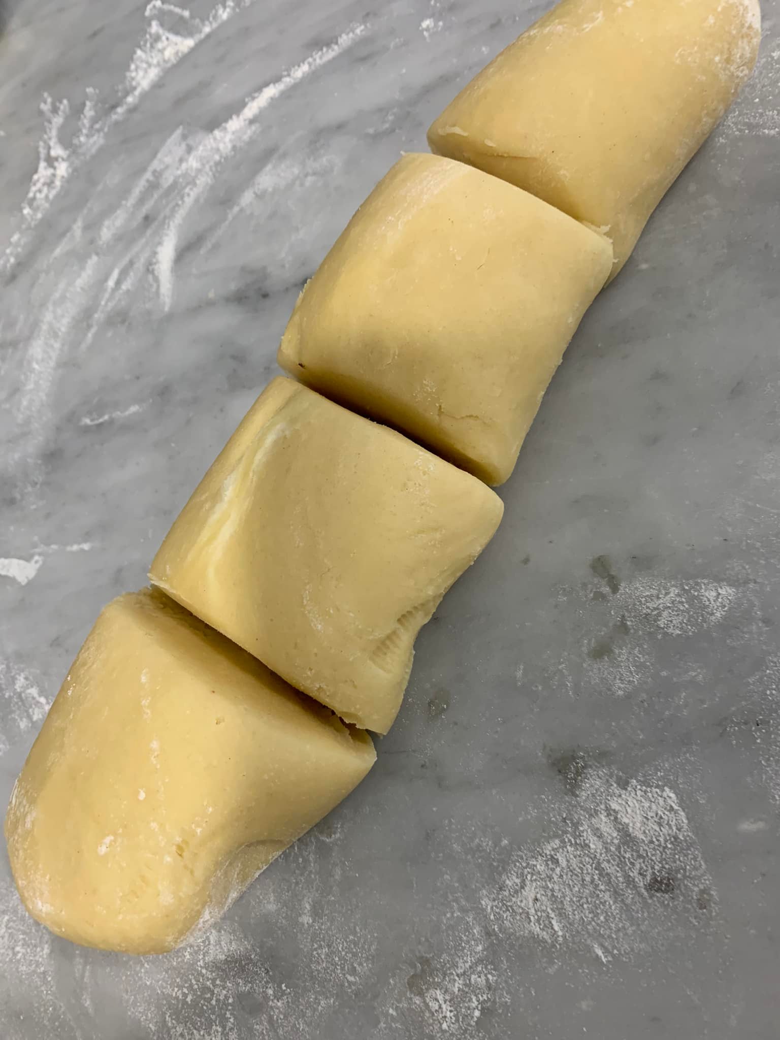 Four logs of raw cookie dough placed on a marble surface ready to be shaped