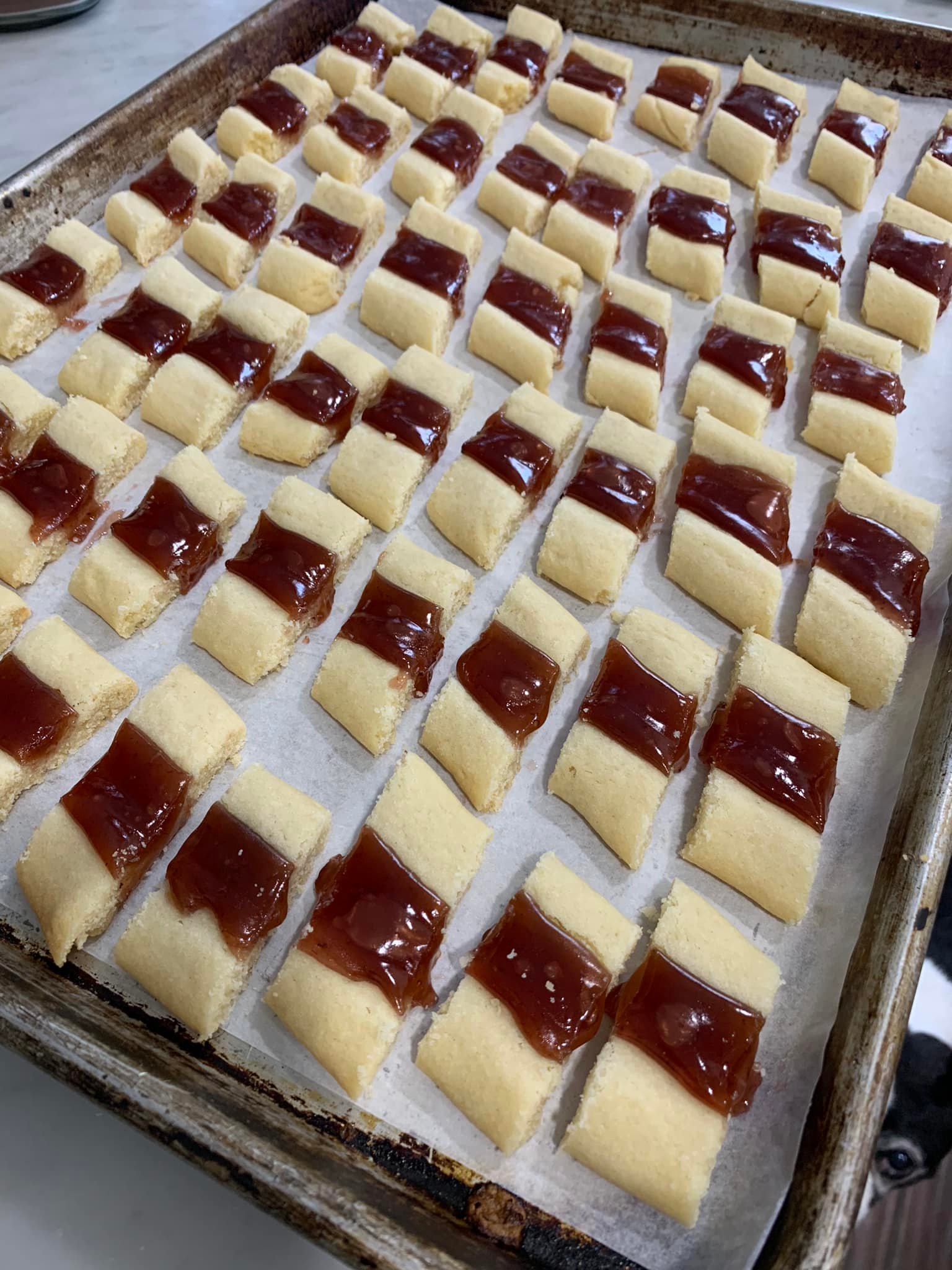 Hundreds of sliced fruit ribbon cookies cooling on a baking sheet