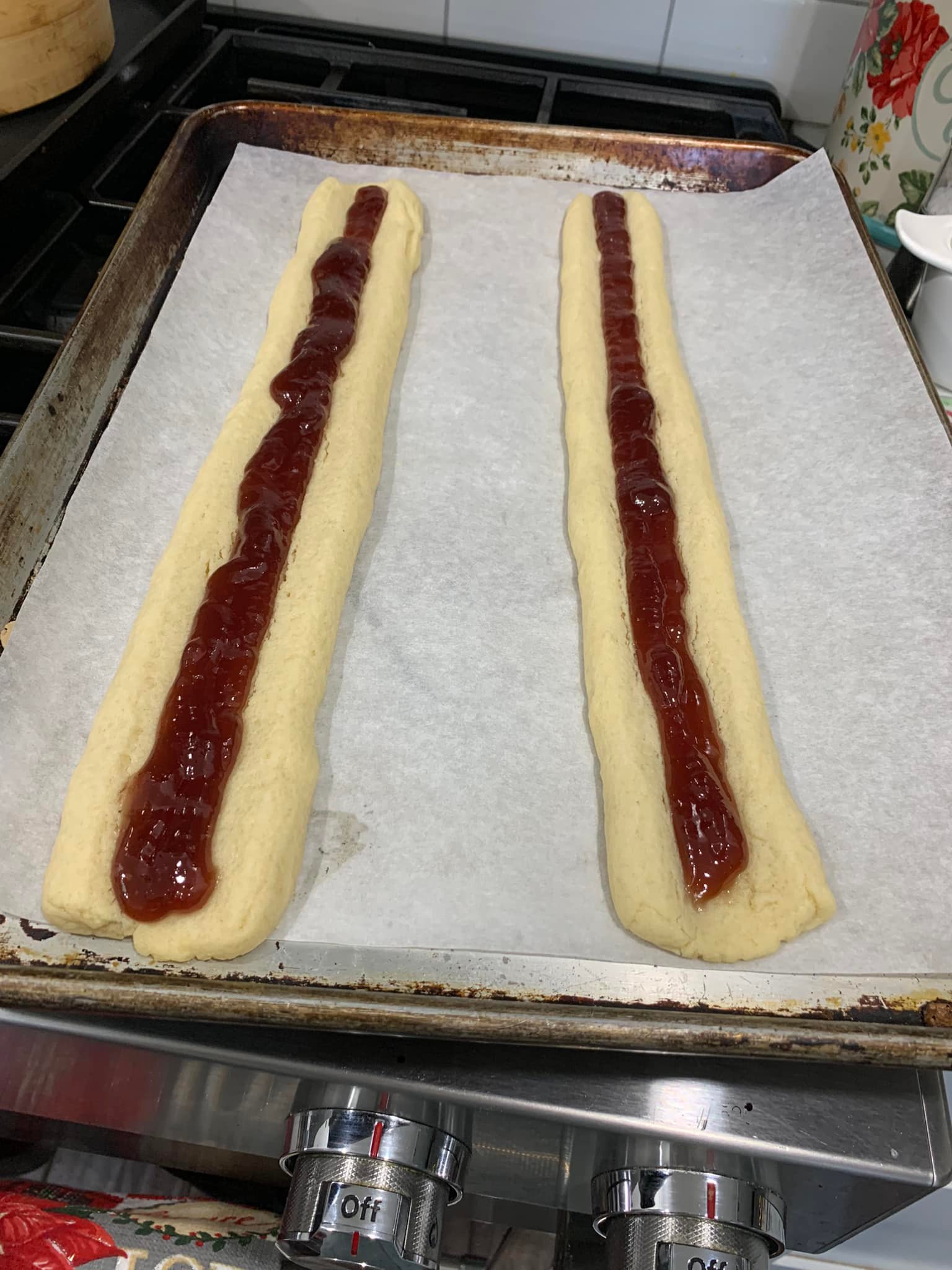 Two baked cookie logs filled with a strip of shiny red raspberry jam