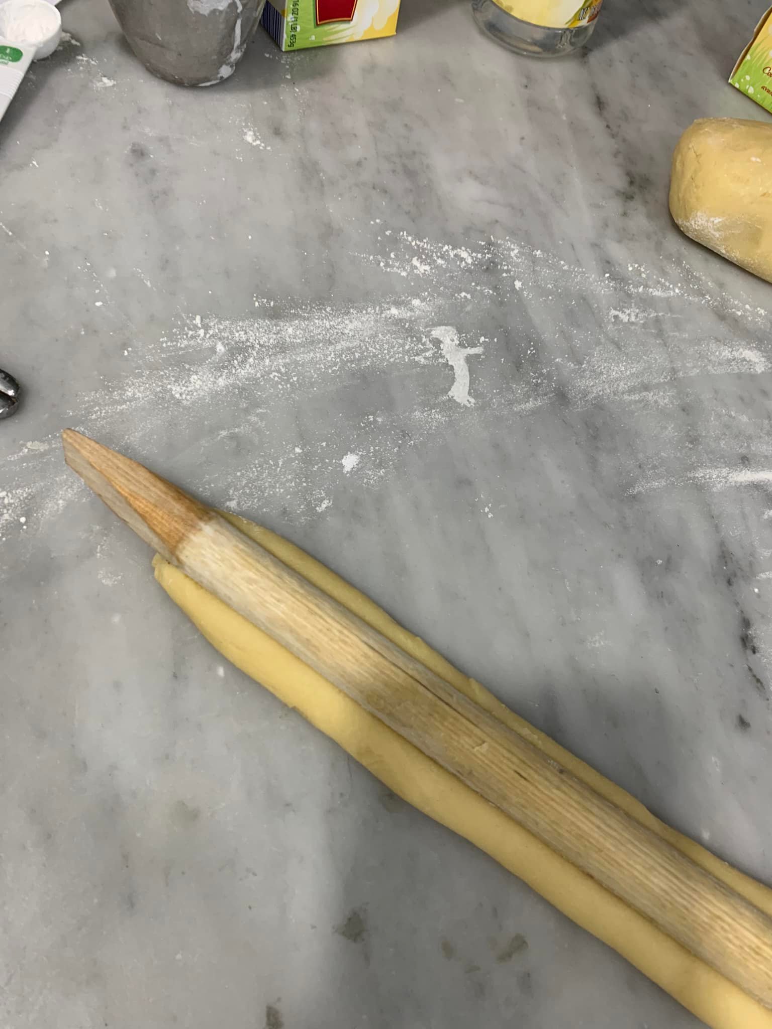 Using a wooden tool handle to press a groove into the center of the cookie dough log