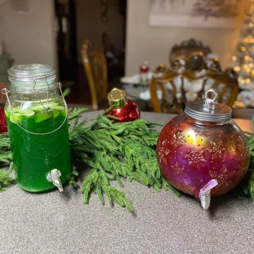 A three-tiered dessert stand filled with white chocolate dipped cookies, chocolate bark, and strawberries filled with cream at a Christmas party.