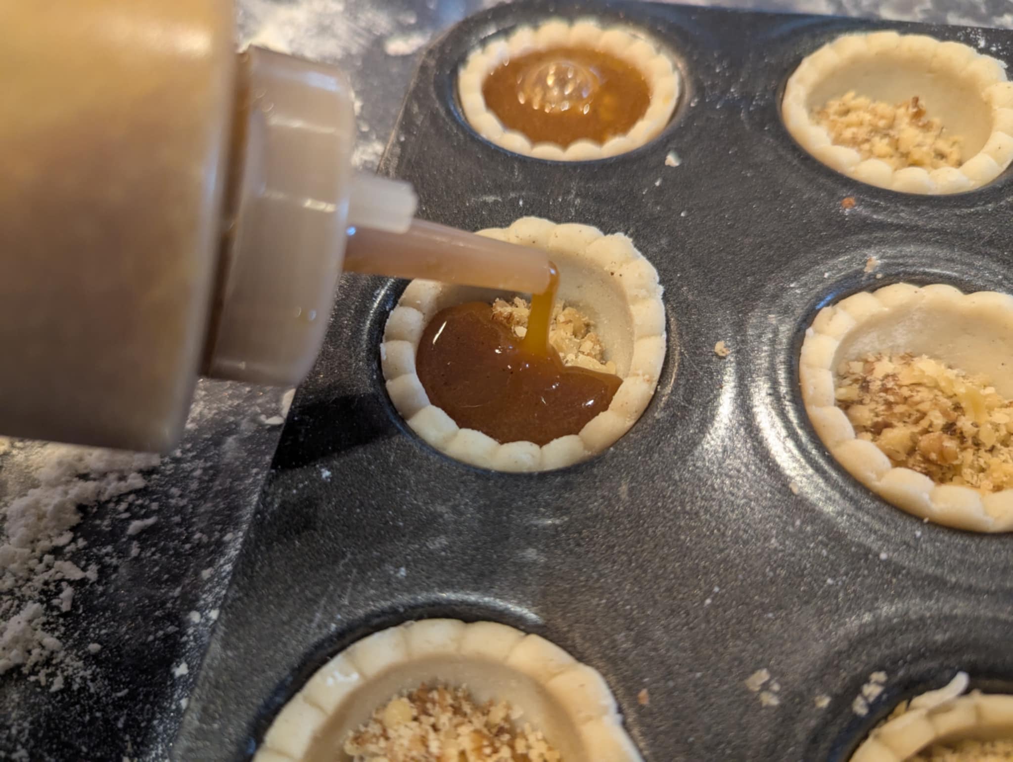 Squeezing brown sugar filling from a plastic condiment bottle into mini tart shells mess-free