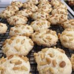 Wire rack filled with golden brown Pignoli cookies covered in toasted pine nuts