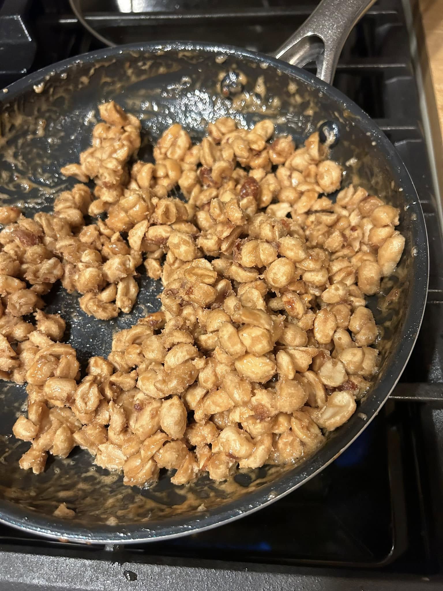 eanuts in a nonstick pan showing the final stage where the maple syrup has crystallized into a dry, sugary coating around the nuts.