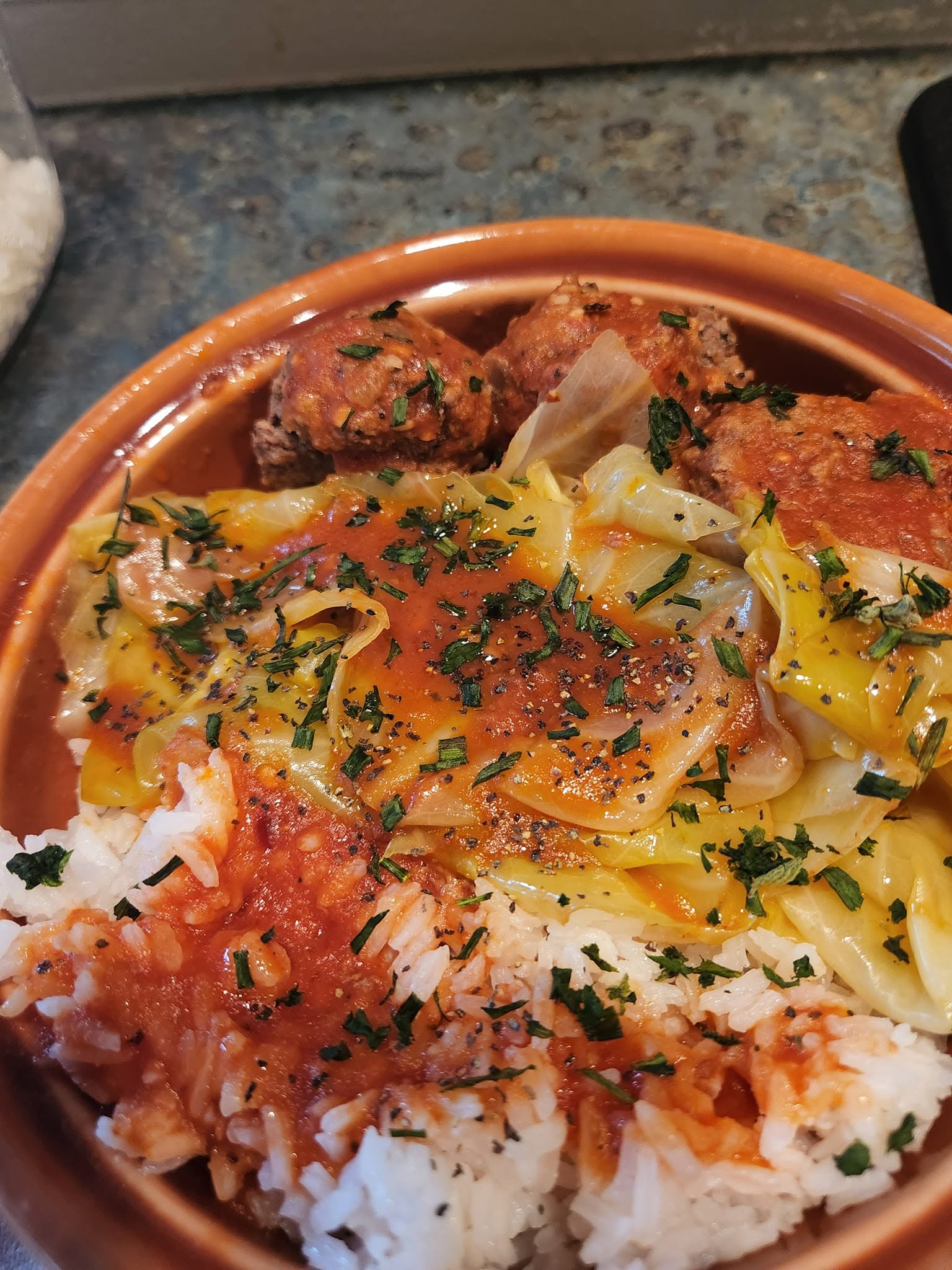 A whole hollowed-out cabbage sitting in a baking dish, filled with meatballs and topped with its own cabbage "lid."