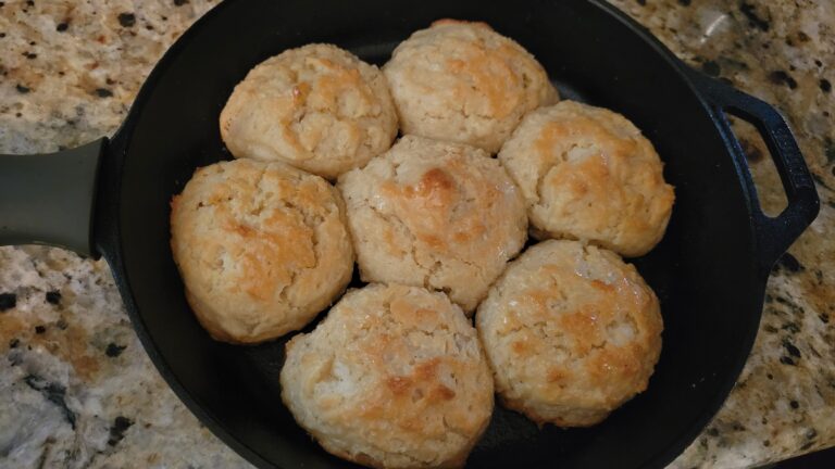 A hot cast iron skillet filled with golden-brown, buttery White Lily drop biscuits straight from the oven.
