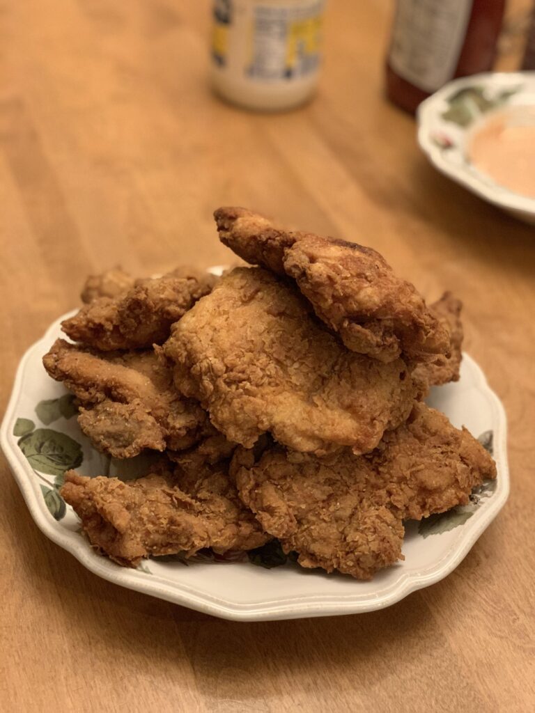 A platter of incredibly crispy, golden brown buttermilk fried chicken resting on a wire cooling rack.