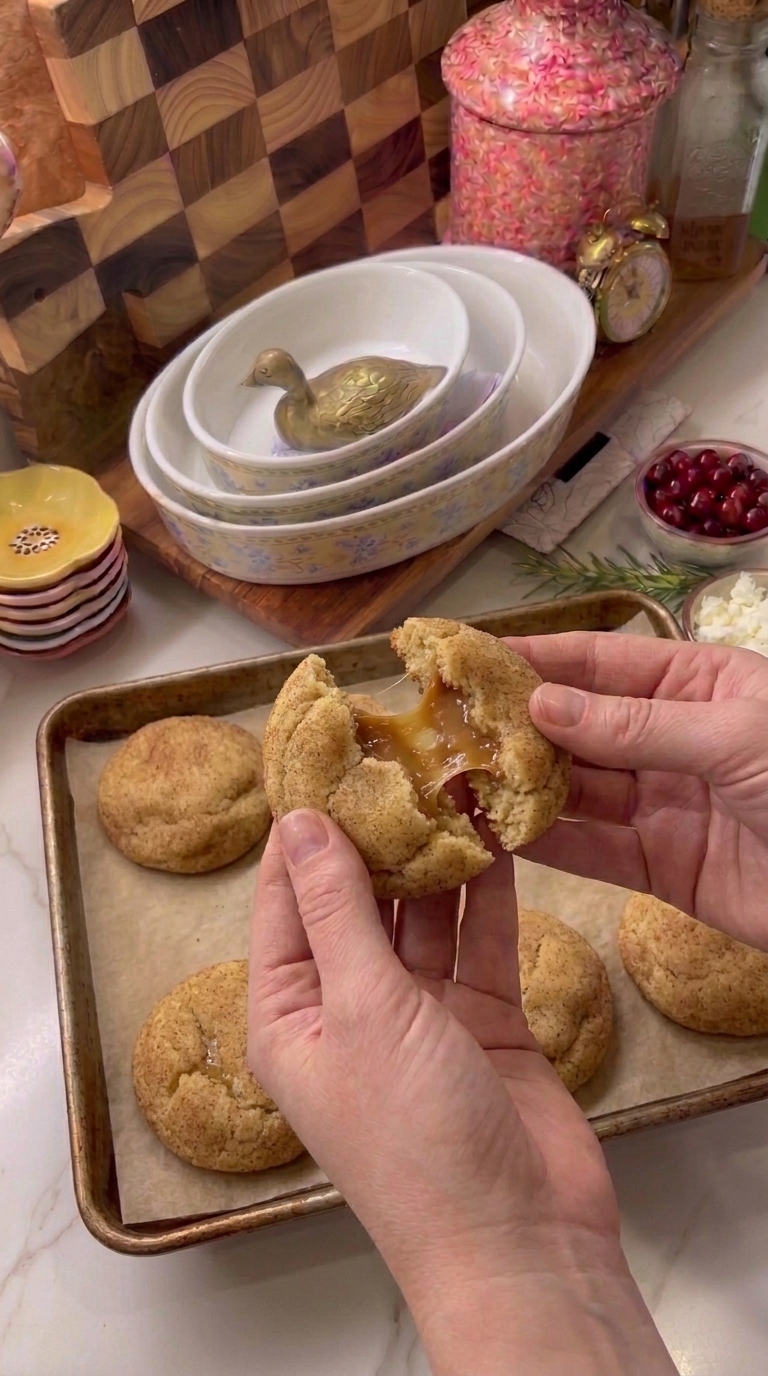 Freshly baked caramel stuffed snickerdoodles with golden cinnamon-sugar coating, including a cookie broken open to show its soft caramel filling.