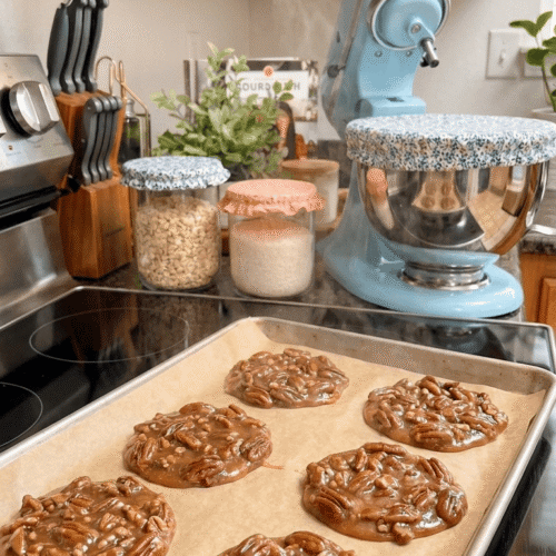 Homemade Southern pecan pralines with whole pecans and creamy caramel-colored candy cooling on a parchment-lined baking sheet